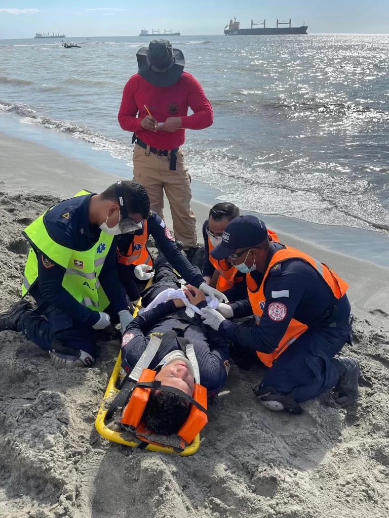 Brigadistas realizando capacitación práctica de rescate y atención de emergencias en zona costera